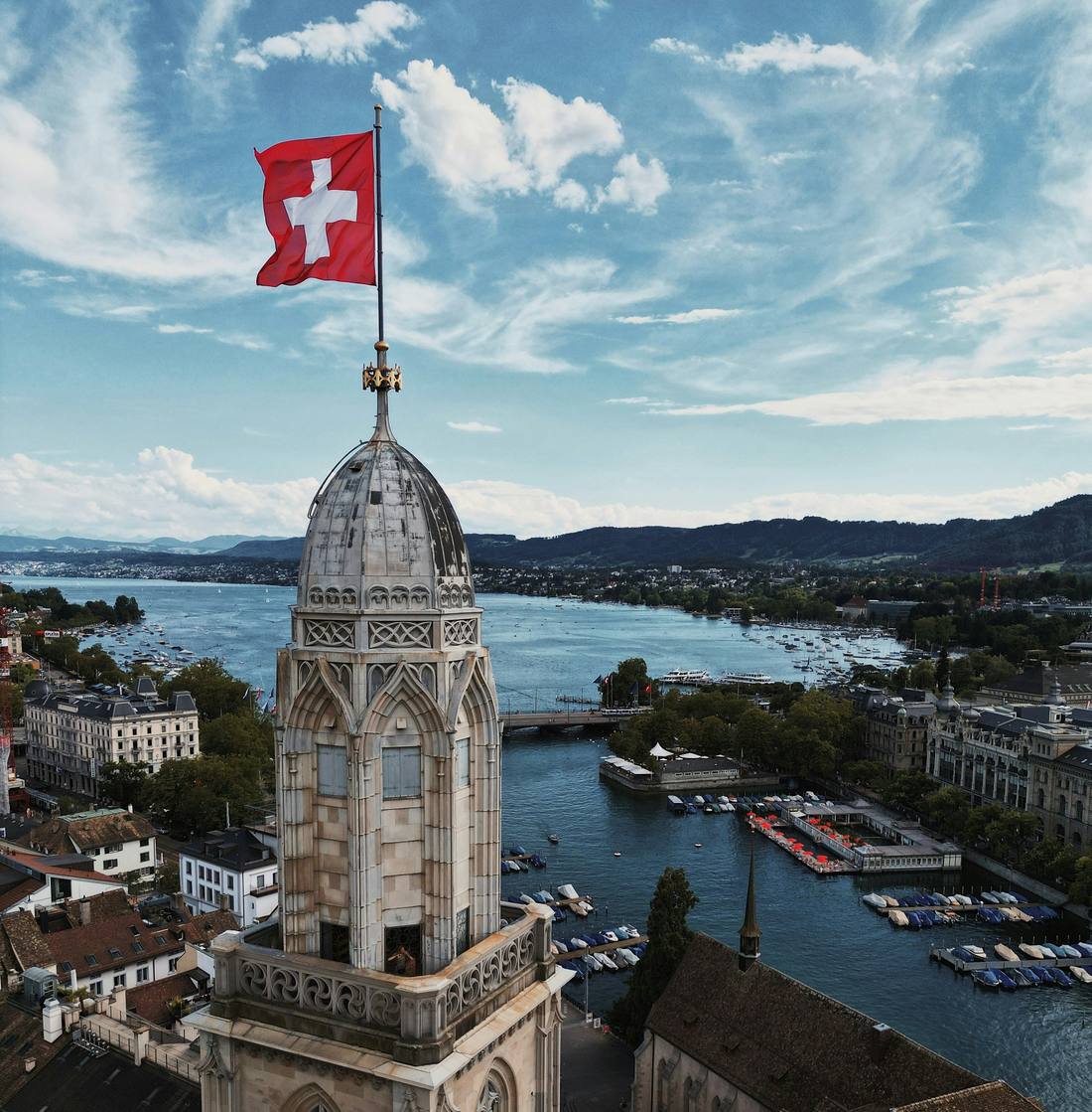 The tower of the Grossmunster in Zurich flying the Swiss flag, with the lake and the city behind it